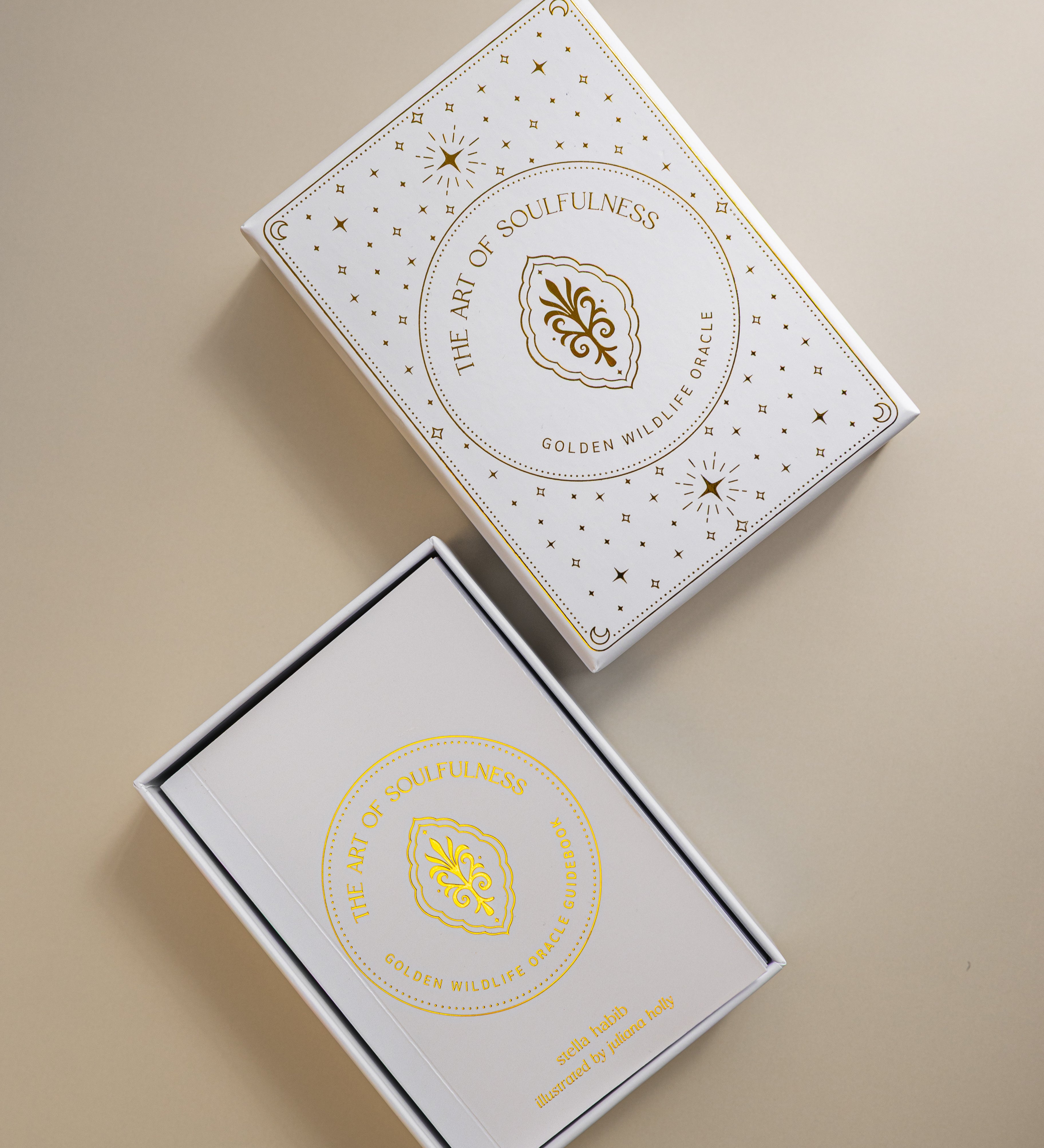 top view of the lid and tray of the gold foiled golden wildlife oracle box, with the cover of the guidebook showing in the tray. 