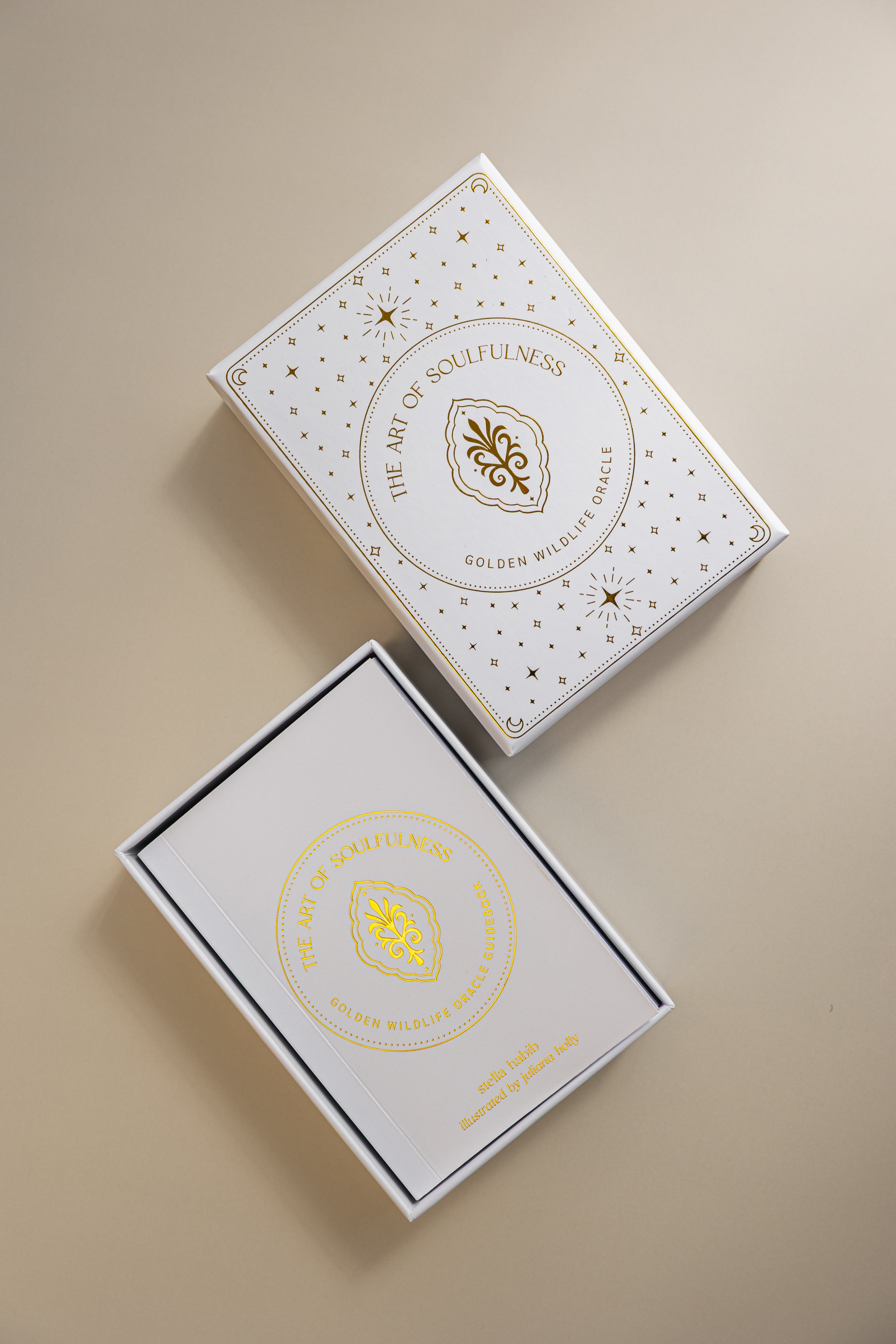 top view of the lid and tray of the gold foiled golden wildlife oracle box, with the cover of the guidebook showing in the tray. 