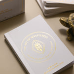 glimmering gold on the cover of the golden wildlife oracle guidebook with the box and cards and the head of a brass turtle in the background.