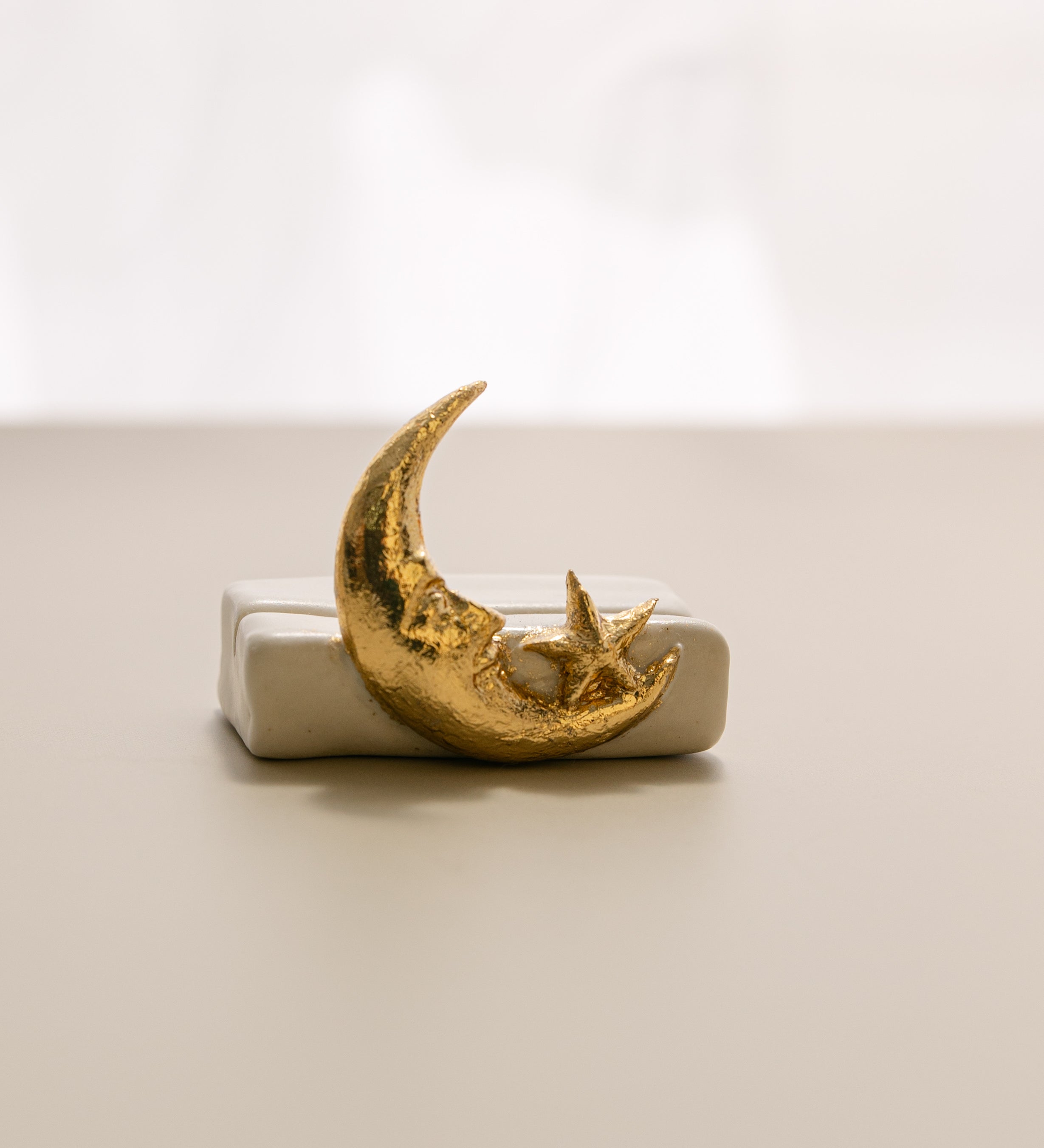 a close-up view of a white matte ceramic oracle card holder with a sculpted moon and star.