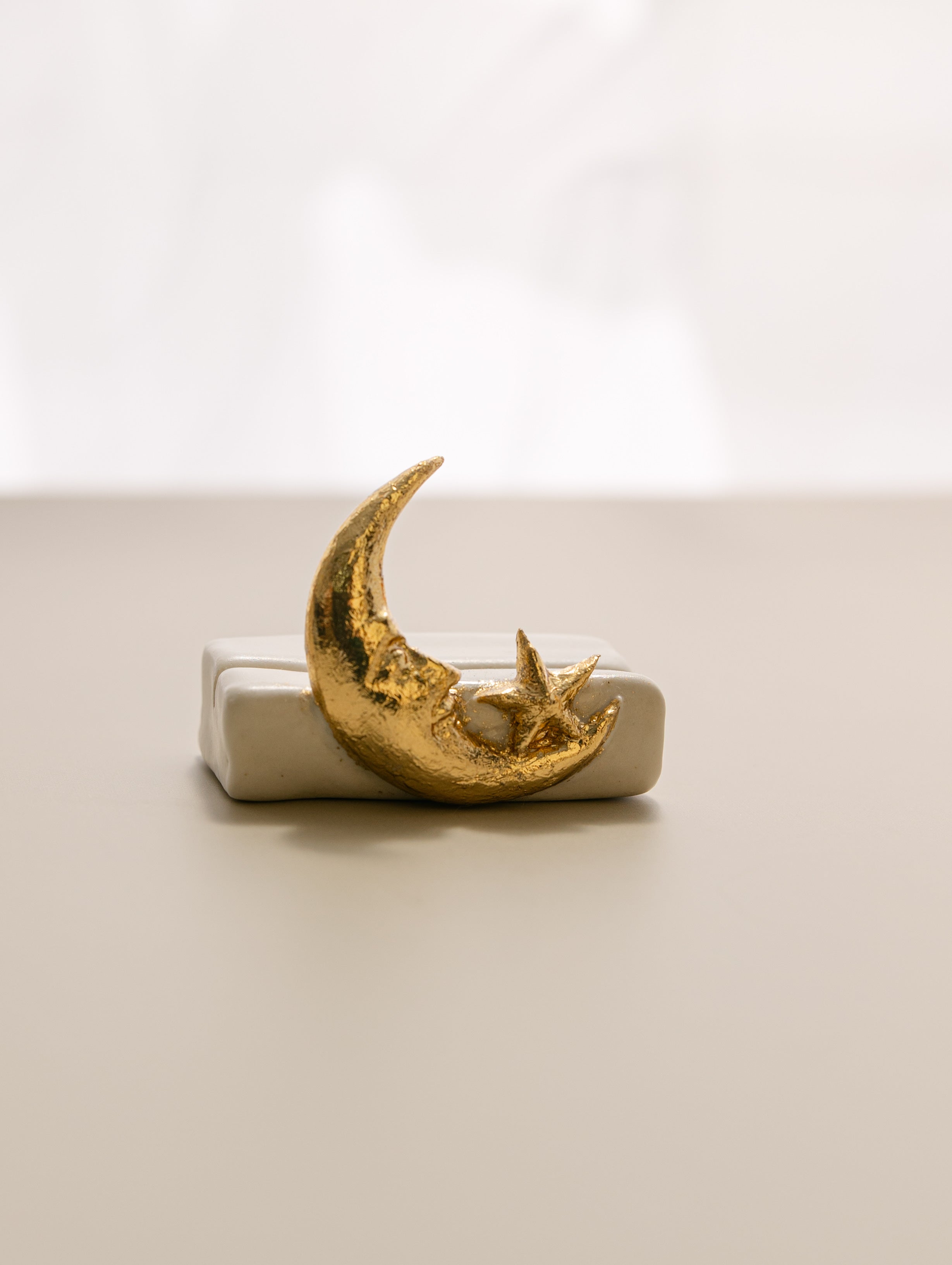 a close-up view of a white matte ceramic oracle card holder with a sculpted moon and star.