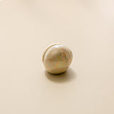 a close-up view of a pearlescent ceramic orb oracle card stand, without an oracle card in it.