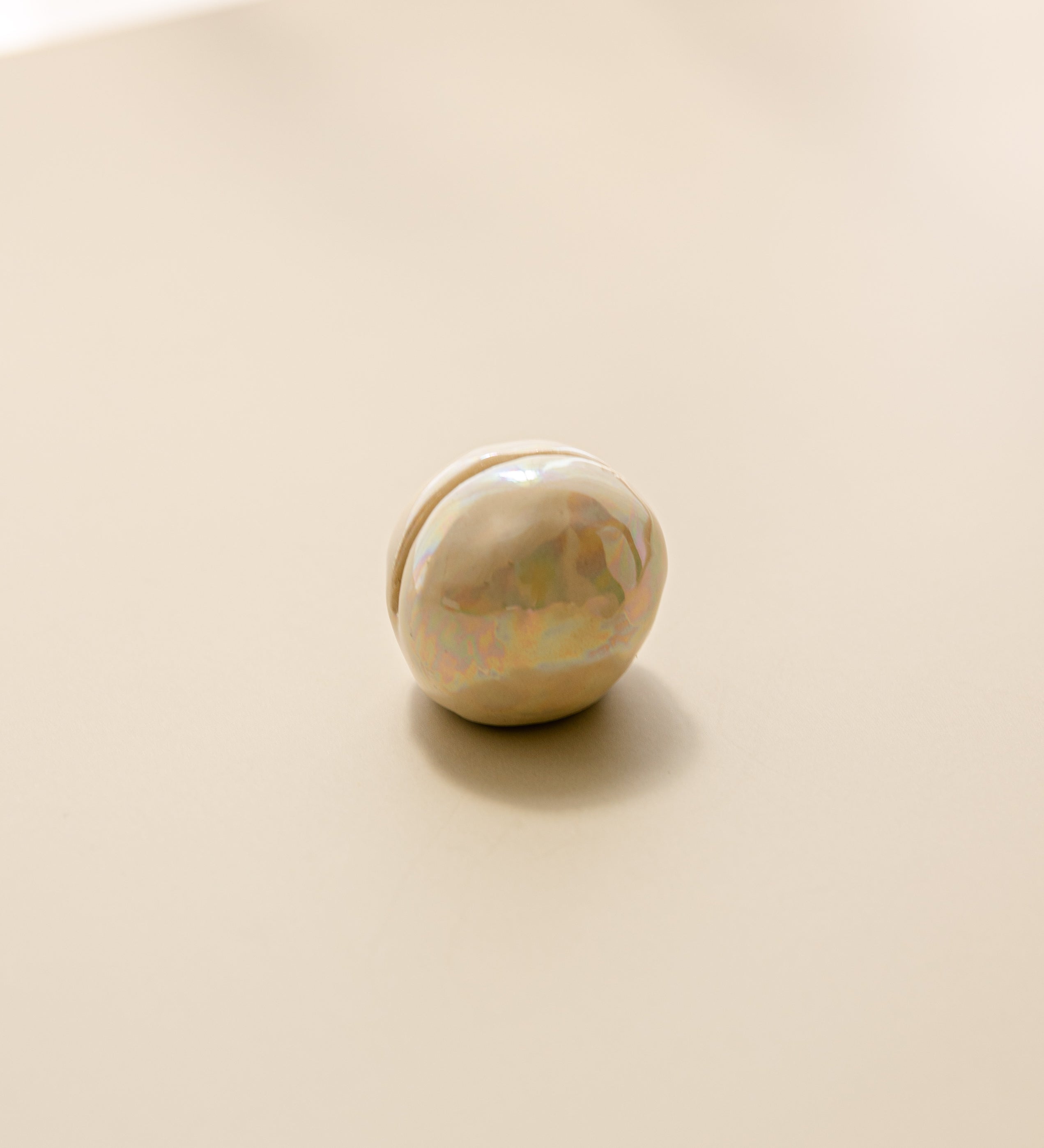 a close-up view of a pearlescent ceramic orb oracle card stand, without an oracle card in it.
