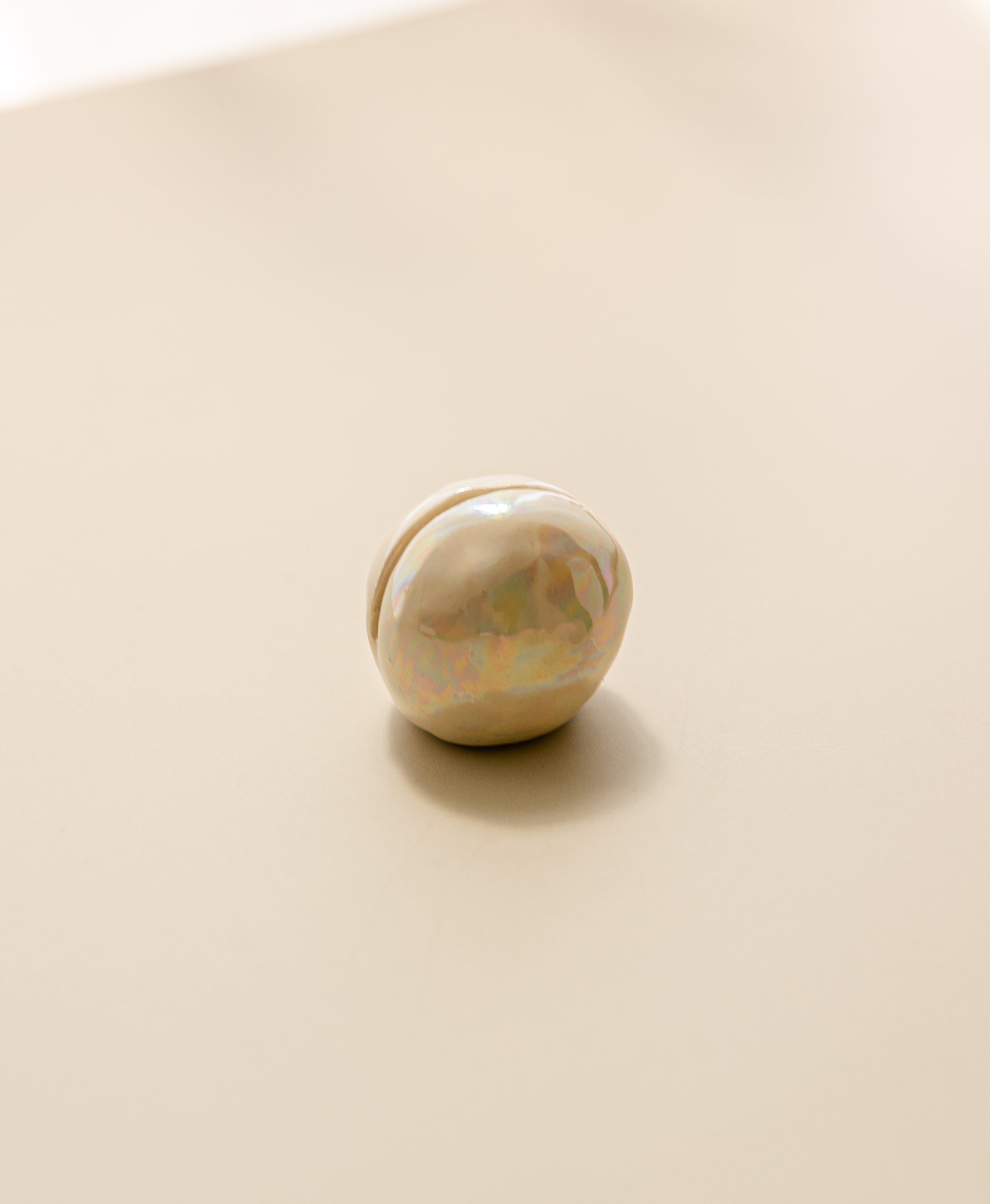 a close-up view of a pearlescent ceramic orb oracle card stand, without an oracle card in it.