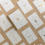 a top view of the golden wildlife oracle box and several of the cards arranged in a face-up grid, with a white aragonite crystal