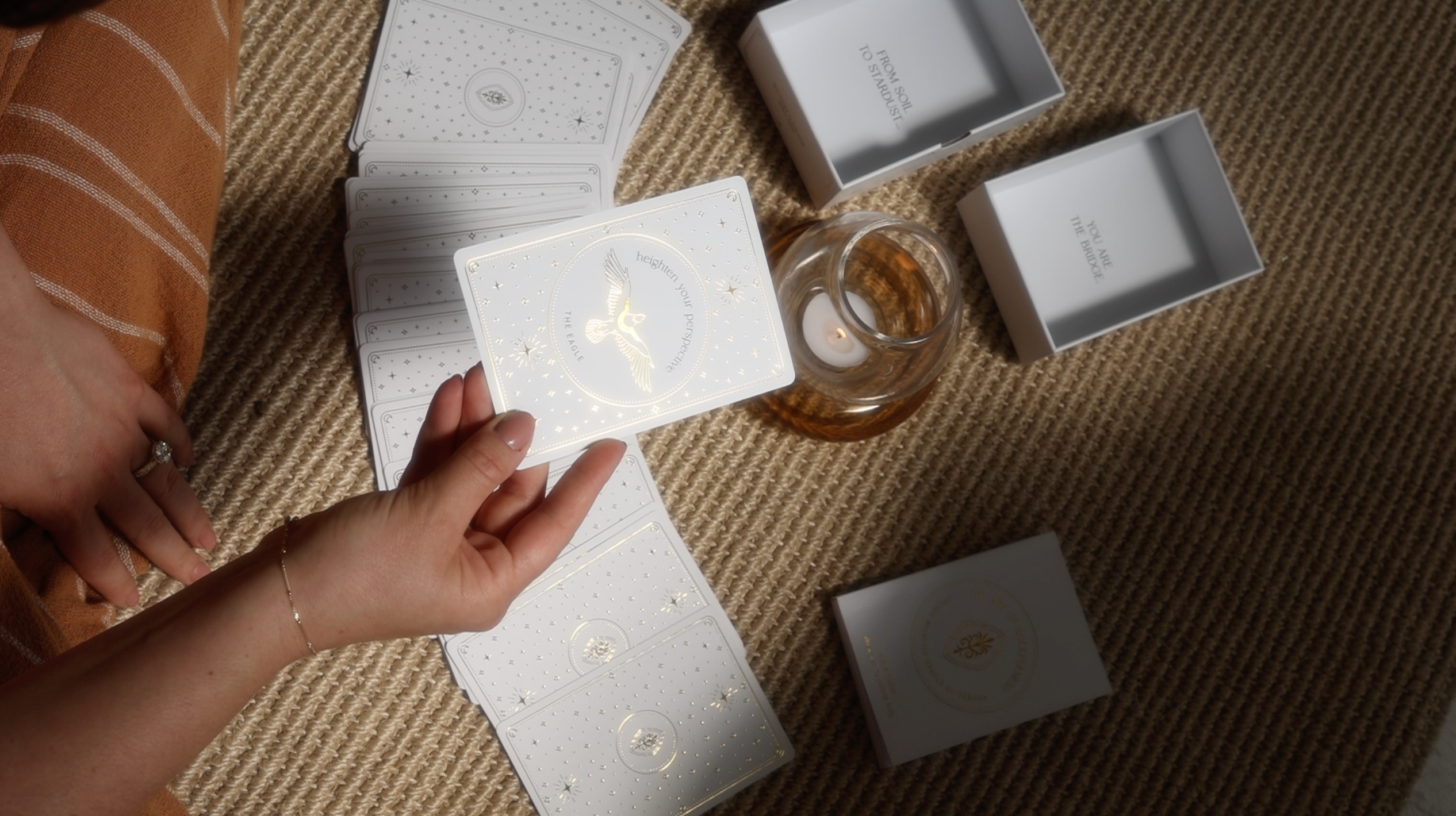 a hand holding a golden wildlife oracle card that says 'heighten your perspective' with an eagle on it, foil details reflecting in the sunlight.
